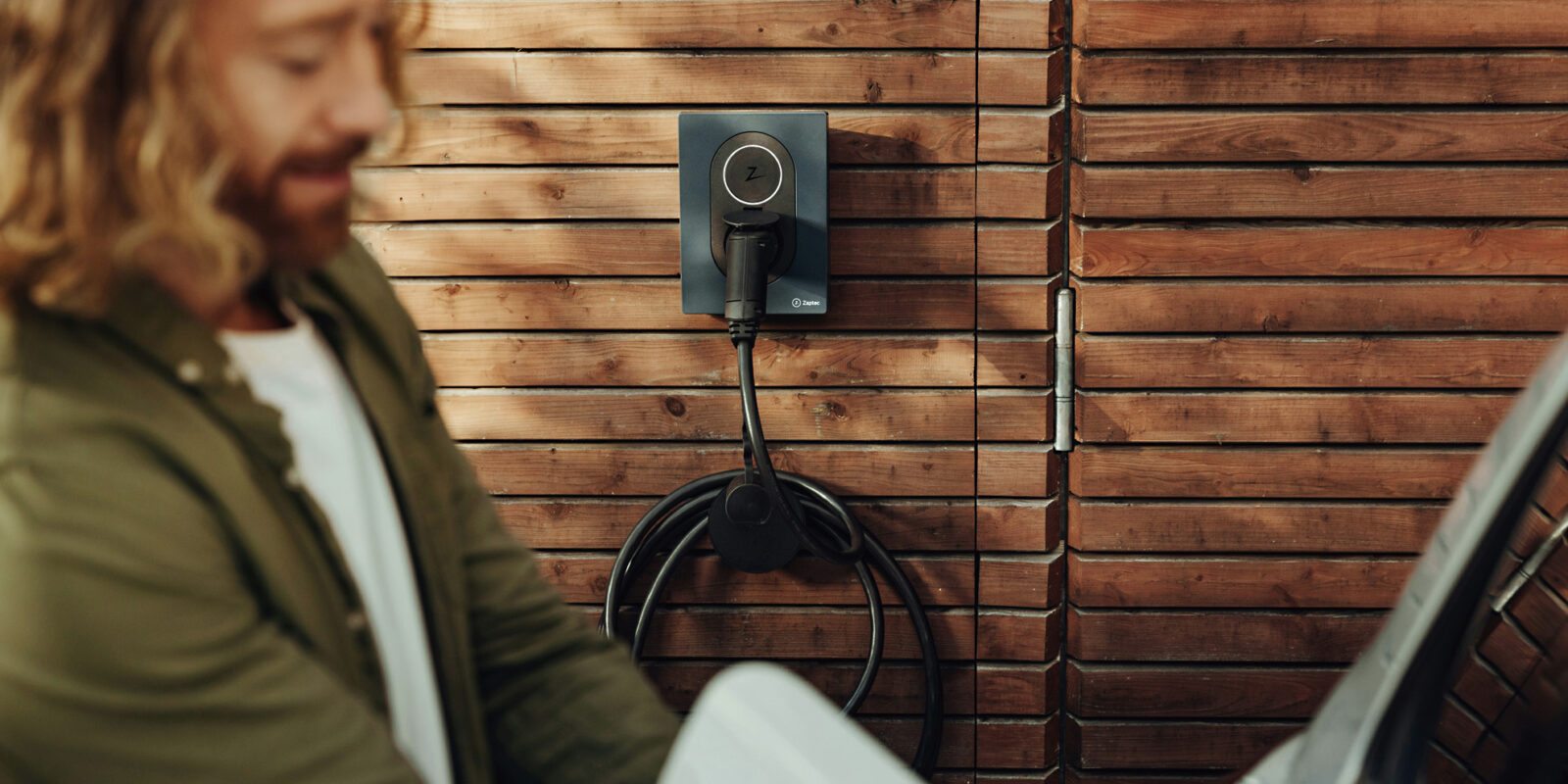 Junger Mann mit Wallbox zum e-Auto laden