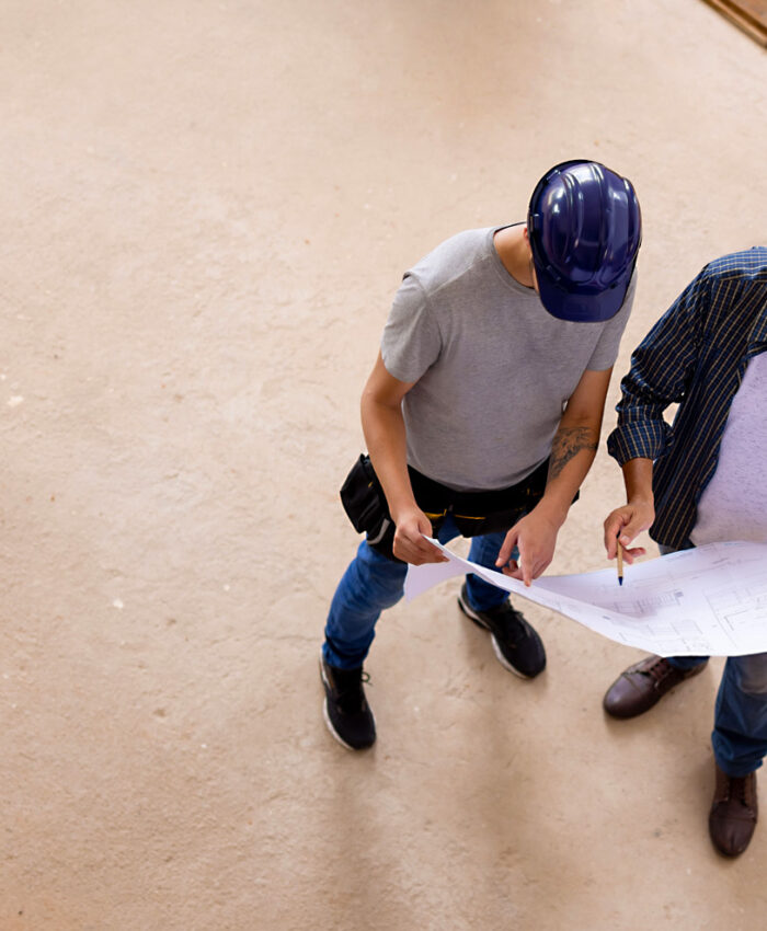 Zwei Männer mit Helm und Konstruktionszeichnung auf Baustelle