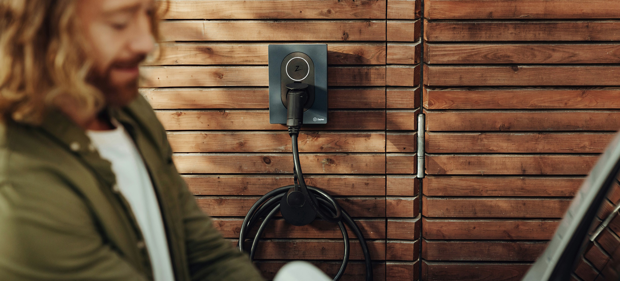 Junger Mann mit Wallbox zum e-Auto laden
