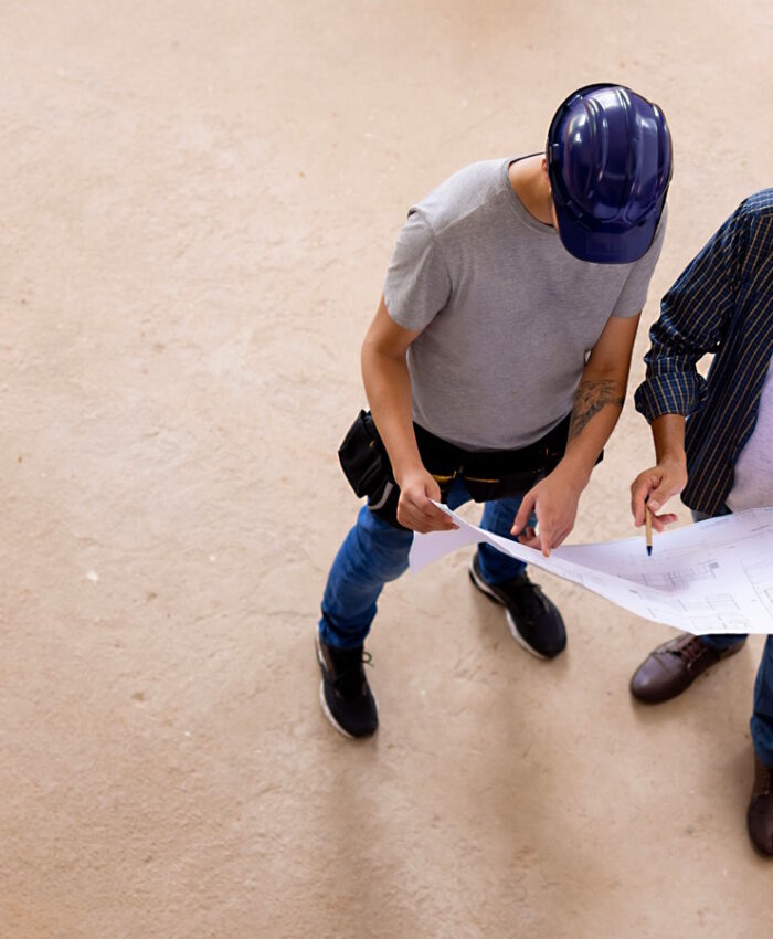 Zwei Männer mit Helm und Konstruktionszeichnung auf Baustelle