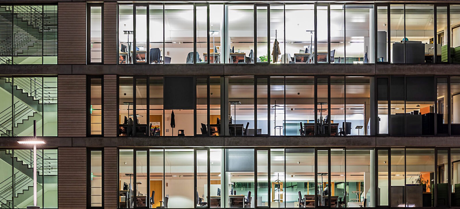 Beleuchtetes Bürogebäude mit 3 sichtbaren Etagen in der Nacht