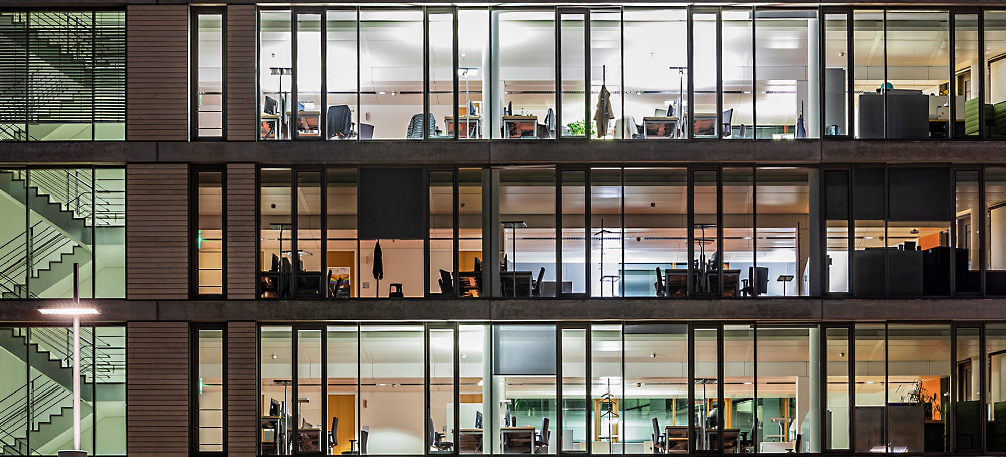 Beleuchtetes Bürogebäude mit 3 sichtbaren Etagen in der Nacht